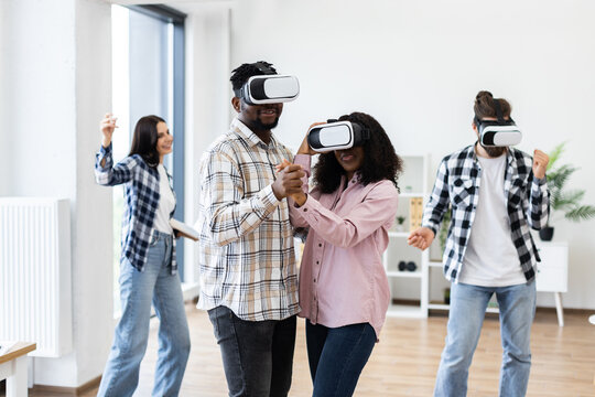 Diverse group of young men and women enjoying time using virtual reality glasses celebrating together indoors. - Powered by Adobe