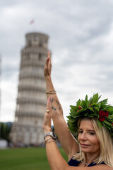 University graduate under the Leaning Tower in Pisa with laurel crown striking iconic pose