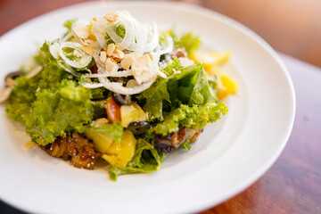 A mixed salad featuring mango, grilled chicken, nuts, and fresh greens served on a white plate. The dish is healthy, colorful, and ready for lunch or a light snack.