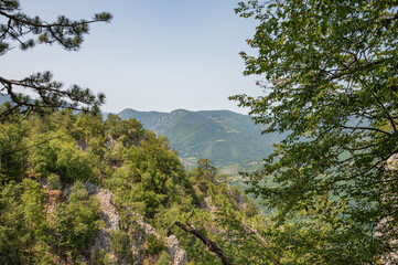 Panoramic view of green forested mountains and valleys under gloomy cloudy sky on natural scenic background.