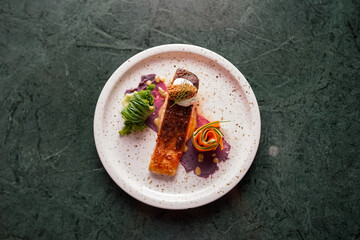 A gourmet dish with crispy-skinned salmon fillet, served with purple yam puree, carrot and cucumber...
