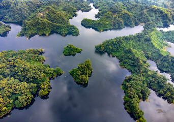 Mohamaya Lake is the second-largest artificial lake in Bangladesh, located in Mirsarai, Chittagong, Bangladesh. Aerial view of a tranquil lake with a pier and docked boats surrounded by lush greenery.