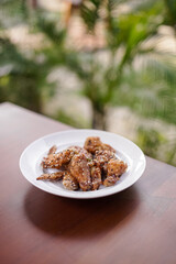 Crispy chicken wings sprinkled with sesame seeds served on white plate, delicious fried appetizer or snack concept.