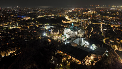 Aerial drone night shot of iconic Lycabettus hill with great views of illuminated city of Athens, Attica, Greece