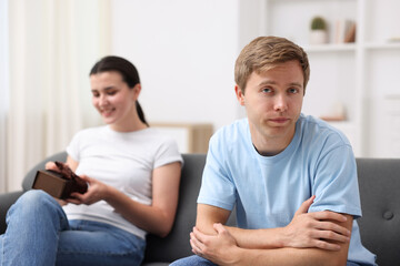 Man feeling jealous of woman receiving gift at home, selective focus