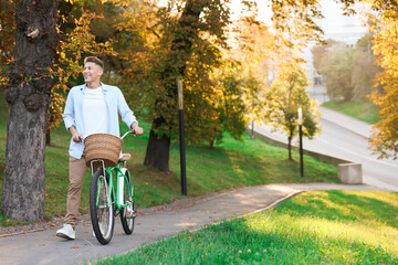 Fototapeta premium Happy man walking his bicycle in park on sunny day. Space for text