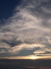 Fototapeta premium Evening sunset with a yellow blue sky – White and grey clouds illuminated by the last remaining rays of the bright yellow evening sun, amidst a darkening blue sky.