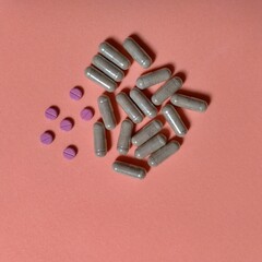 seis píldoras de color rojo con raya en centro y varias cápsulas transparentes con polvo color marrón.  en conjunto a su lado, farmacia, química, medicina © Elena G. Madrid