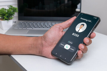 Right to disconnect law concept. Hand holding smartphone with incoming call from Boss or Manager at night after business hours.