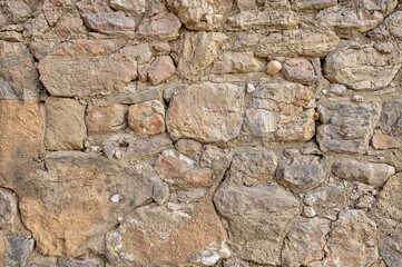 Fototapeta premium Stunning antique wall surface from a 14th-century fortress, featuring colorful, three-dimensional stones ideal for design and wallpaper with a coarse sandy feel.