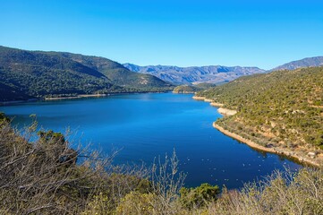 Fototapeta premium Dam on the Vasilikos River nestled among hills and forests, a favored destination for fishing and hiking enthusiasts.