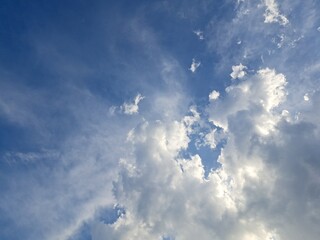 Late afternoon sun illuminating the clouds in the blue sky – White and grey clouds illuminated by the strong rays of the late afternoon sun, amidst a blue sky.