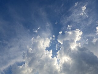 Late afternoon sun illuminating the clouds in the blue sky – White and grey clouds illuminated by the strong rays of the late afternoon sun, amidst a blue sky.