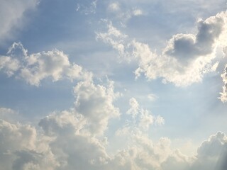 Late afternoon sun illuminating the clouds in the blue sky – White and grey clouds illuminated by the strong rays of the late afternoon sun, amidst a blue sky.