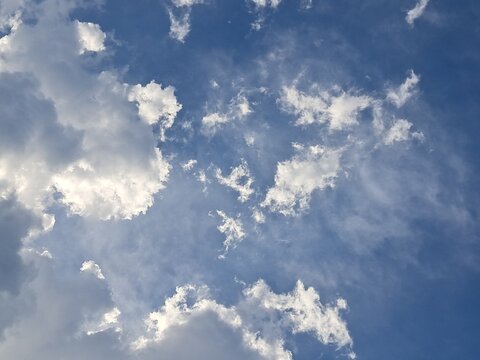 Late afternoon sun illuminating the clouds in the blue sky – White and grey clouds illuminated by the strong rays of the late afternoon sun, amidst a blue sky.