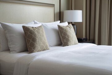 White Linen Bedding on a Double Bed with Hypoallergenic Pillows and Decorative Cushions, Side Perspective of a Guest Room in a Hotel. Interior and Home Decoration Concepts