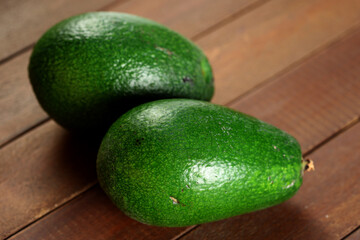 Close-up of two fresh avocados on wooden surface