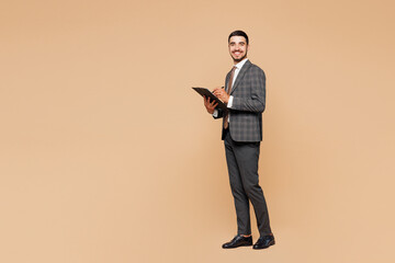 Full body young successful employee business man corporate lawyer wear classic formal grey suit shirt tie work in office hold clipboard with paper account documents isolated on plain beige background.