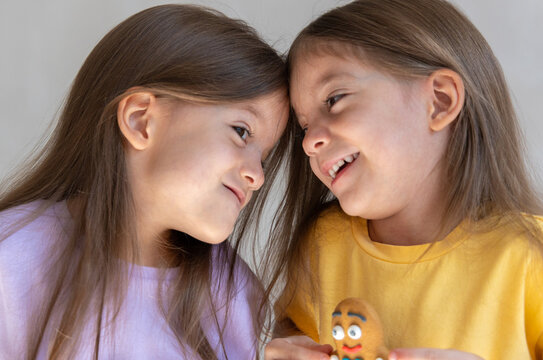 Portrait of two happy brunette little sisters bonding to each other and smiling, looking each other