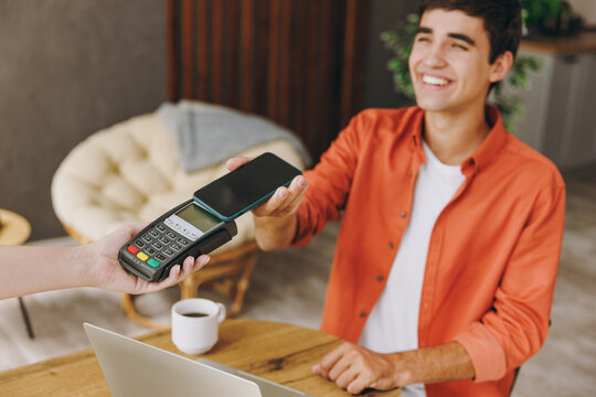 Young man wears casual clothes hold bank payment terminal process acquire cell phone sit at table in coffee shop cafe relax rest in free time indoor Freelance mobile office concept. Focus on object .