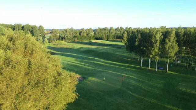 Valmiera, Latvia - August 27, 2025 - Golden sunrise over Avoti Golf Course with long shadows stretching across manicured greens and trees, creating a peaceful and scenic morning landscape.
