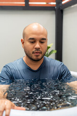 Man practices cold therapy and ice bathing in inflatable tub, using Wim Hof Method for wellness,...