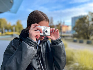 Young woman using an old compact camera, symbolizing return to analogue media and authentic...