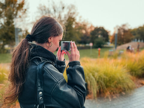 een girl exploring vintage photography with retro point-and-shoot camera outdoors. Embracing analogue lifestyle, slow living, and nostalgic digital minimalism.