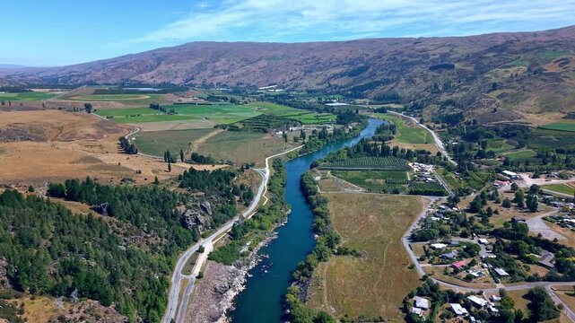 Aerial drone footage captures famous iconic scenic New Zealand landscape following one of New Zealand's most powerful, and longest rivers the clutha downstream on beautiful sunny day.