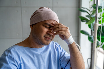 Asian male cancer patient sits in a wheelchair with an IV drip stress and sadness reflecting the...