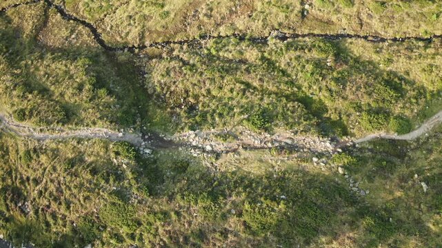 Peaceful drone shot of a person walking along a lush green alpine path in K&uuml;htai, Tyrol. Ideal for wellness, nature or tourism visuals.