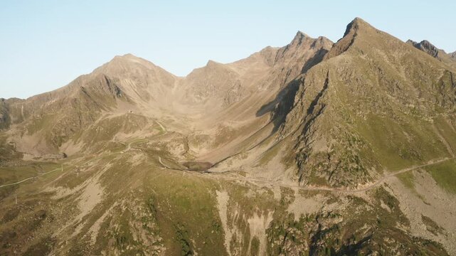 A wide drone shot of an alpine valley with a serene mountain lake, surrounded by rocky peaks in K&uuml;htai. Ideal for travel, nature, or landscape content.