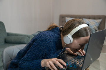 Young woman wearing headphones leans very close to her laptop screen while intensely gaming with a mouse in her hand, showcasing extreme focus and engagement in the virtual world
