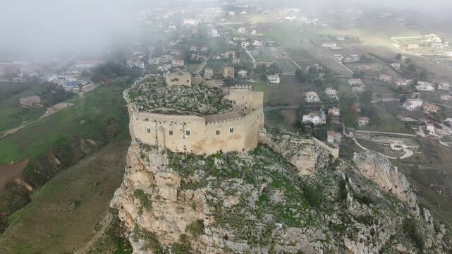 Aerial 4k drone footage of Mussomeli Castle in Sicily, Italy, featuring the historic fortress, dramatic misty atmosphere, surrounding hills, and panoramic views of the landscape