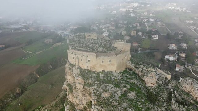 Aerial 4k drone footage of Mussomeli Castle in Sicily, Italy, featuring the historic fortress, dramatic misty atmosphere, surrounding hills, and panoramic views of the landscape