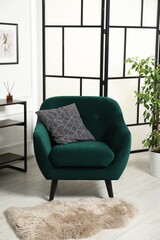 Stylish armchair with pillow, console table and houseplant indoors. Interior design
