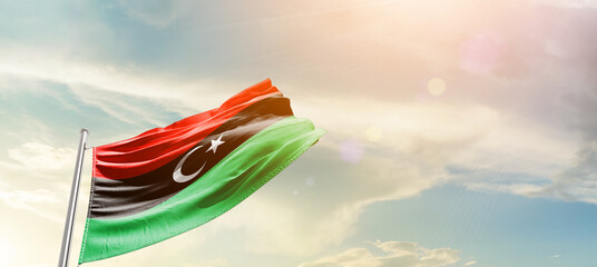 Libya flag waving proudly under a bright sky with text happy independence day. Libya national flag...