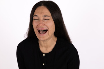 Woman laughing heartily, eyes closed, mouth wide open in joyous moment capture