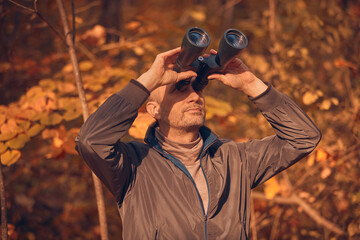 Fototapeta premium Amateur birdwatcher observing birds and other animals in nature with binoculars.