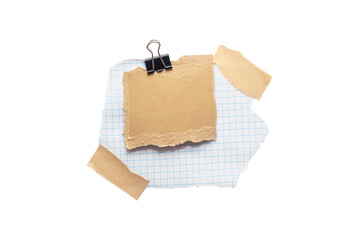 Torn piece of school notebook in a grid and brown piece of paper with beige tape and black binder isolated on white background