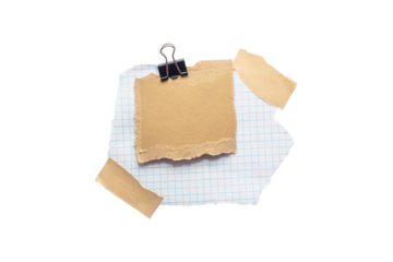 Torn piece of school notebook in a grid and brown piece of paper with beige tape and black binder isolated on white background