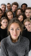 A group of people are smiling and posing for a photo. The woman in the center is the main focus of the image