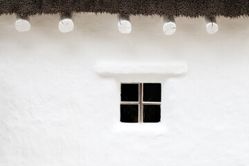 window in wall of old house with thatched roof