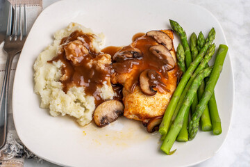 chicken breast top with gravy and mushrooms