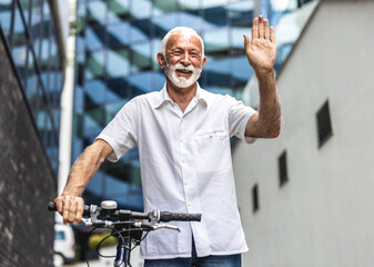 Senior man traveling through the city with her bike. Man with bicycle waving.
