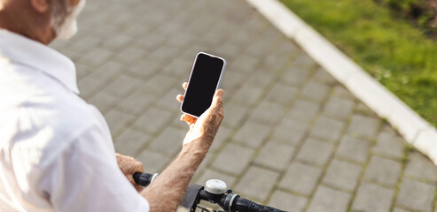 Unrecognisable man with bike using smartphone. Casual handsome senior businessman is going to work by bicycle. He is standing next to bike and using smart phone.