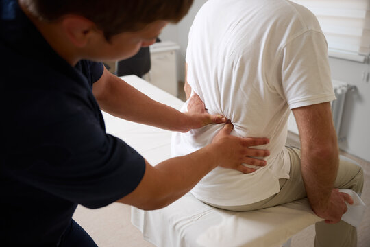 Chiropractor performing manual back adjustment on patient in medical clinic. Physiotherapy, spinal alignment, and rehabilitation treatment for lower back pain relief.