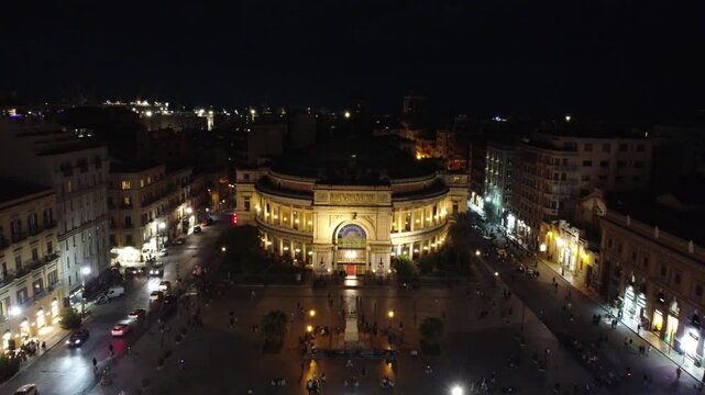 Aerial 4k drone footage of Teatro Politeama Garibaldi and surrounding square in Palermo, Sicily, Italy at night, showcasing illuminated architecture, city streets, and vibrant urban nightlife