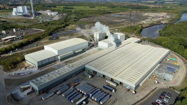 Drone aerial footage of Yorkshire industrial manufacturing site showing factory warehouse, smoke stack plume and River Aire landscape environment