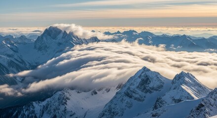 Aerial view of snow capped mountain range with clouds filling the valleys at sunset or sunrise light